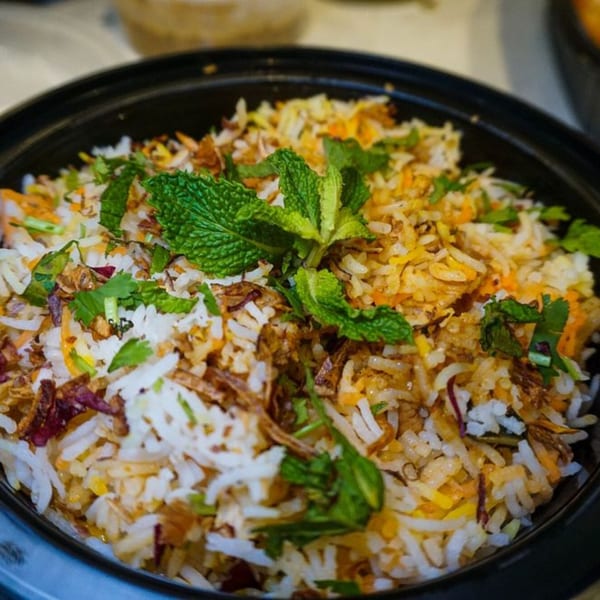 Close-up of Chit Chaat Cafe's Indian biryani, garnished with fresh mint and cilantro.