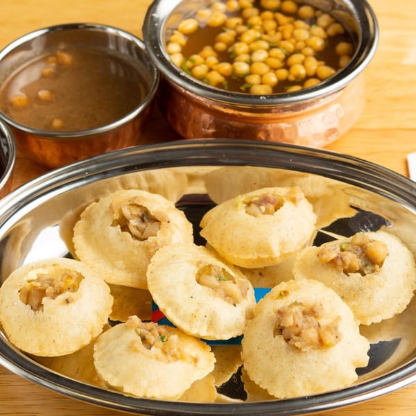 Pani Puri on a silver platter with two copper bowls of pani and boondi.