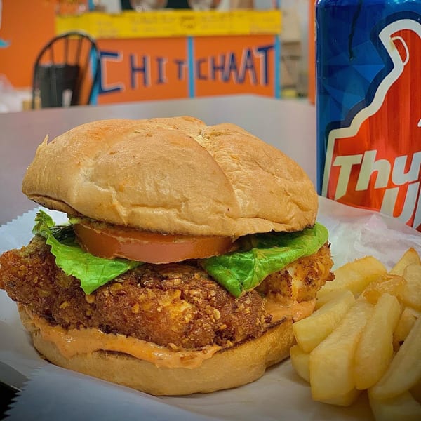Chit Chaat Cafe's fried chicken sandwich with lettuce, tomato, fries, and a Thums Up soda.
